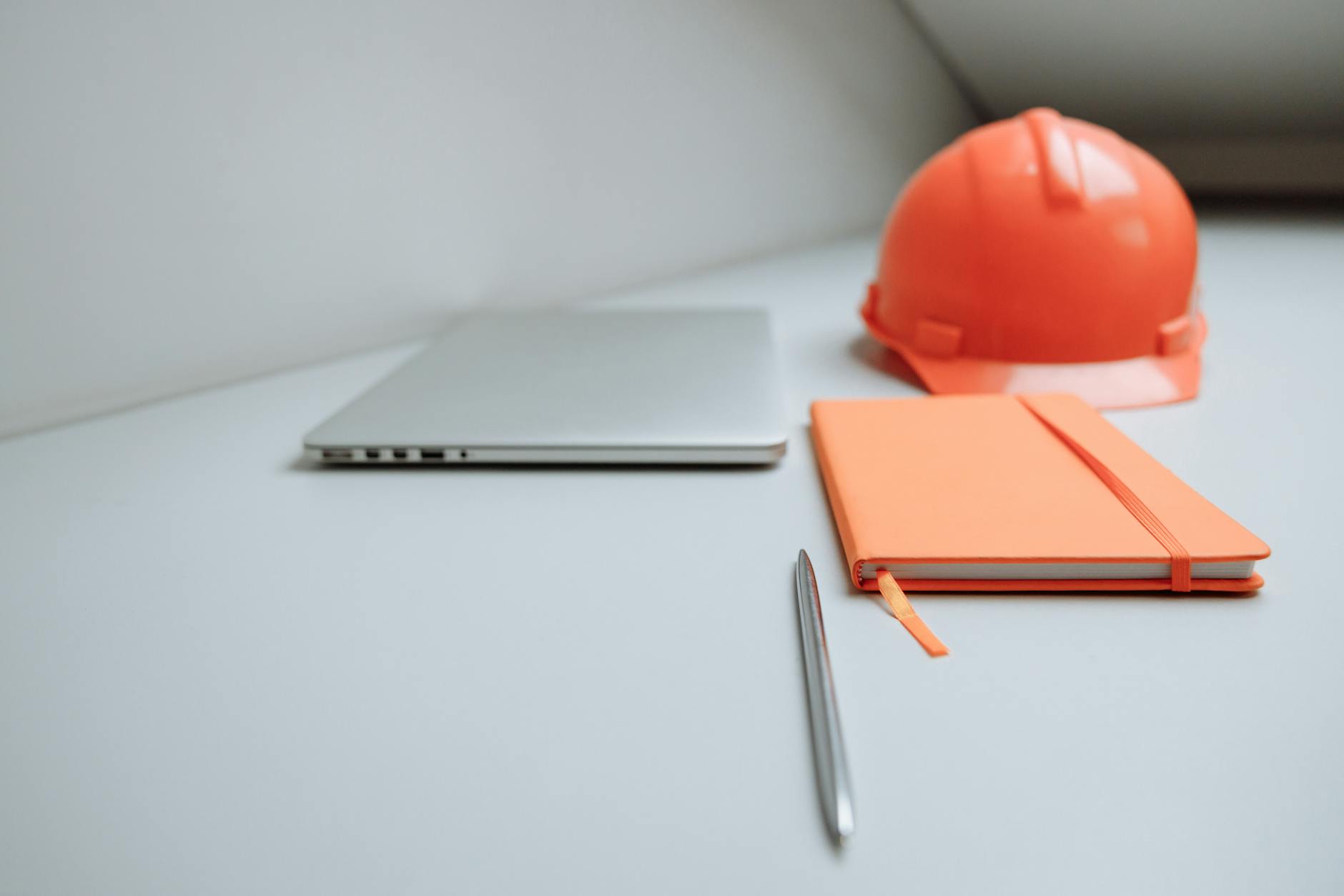 Biuro z laptopem, notesem i kaskiem ochronnym na biurku