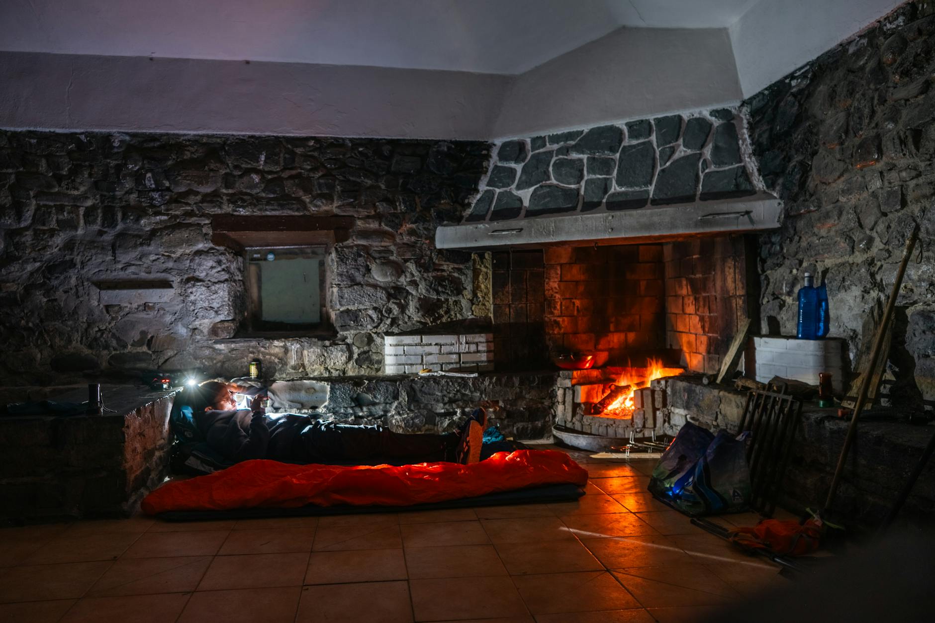 Osoba śpiąca w środku kampera obok ciepłego, rozpalonego kominka