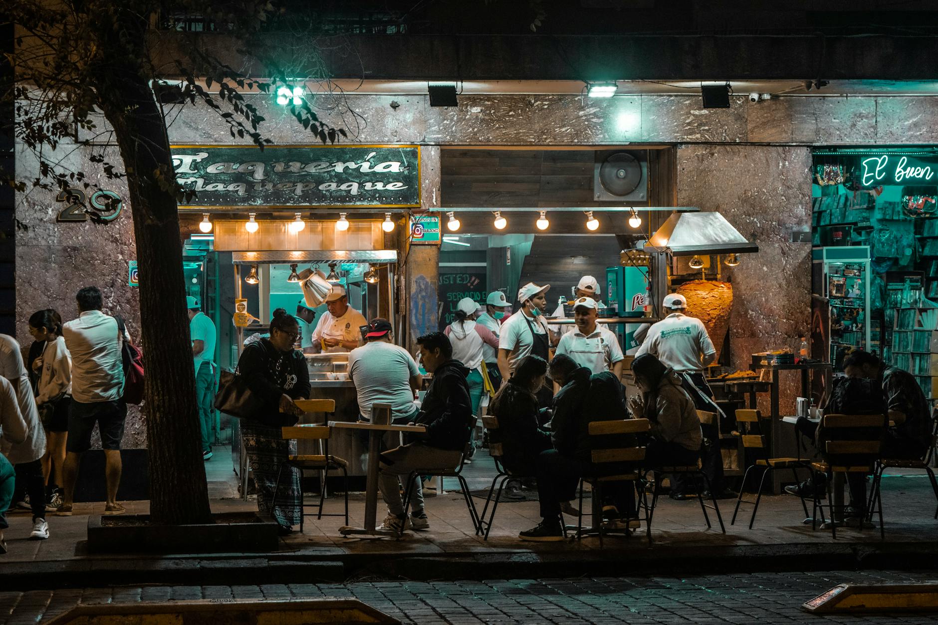 Tłoczna uliczna restauracja w nocnym, oświetlonym centrum miasta