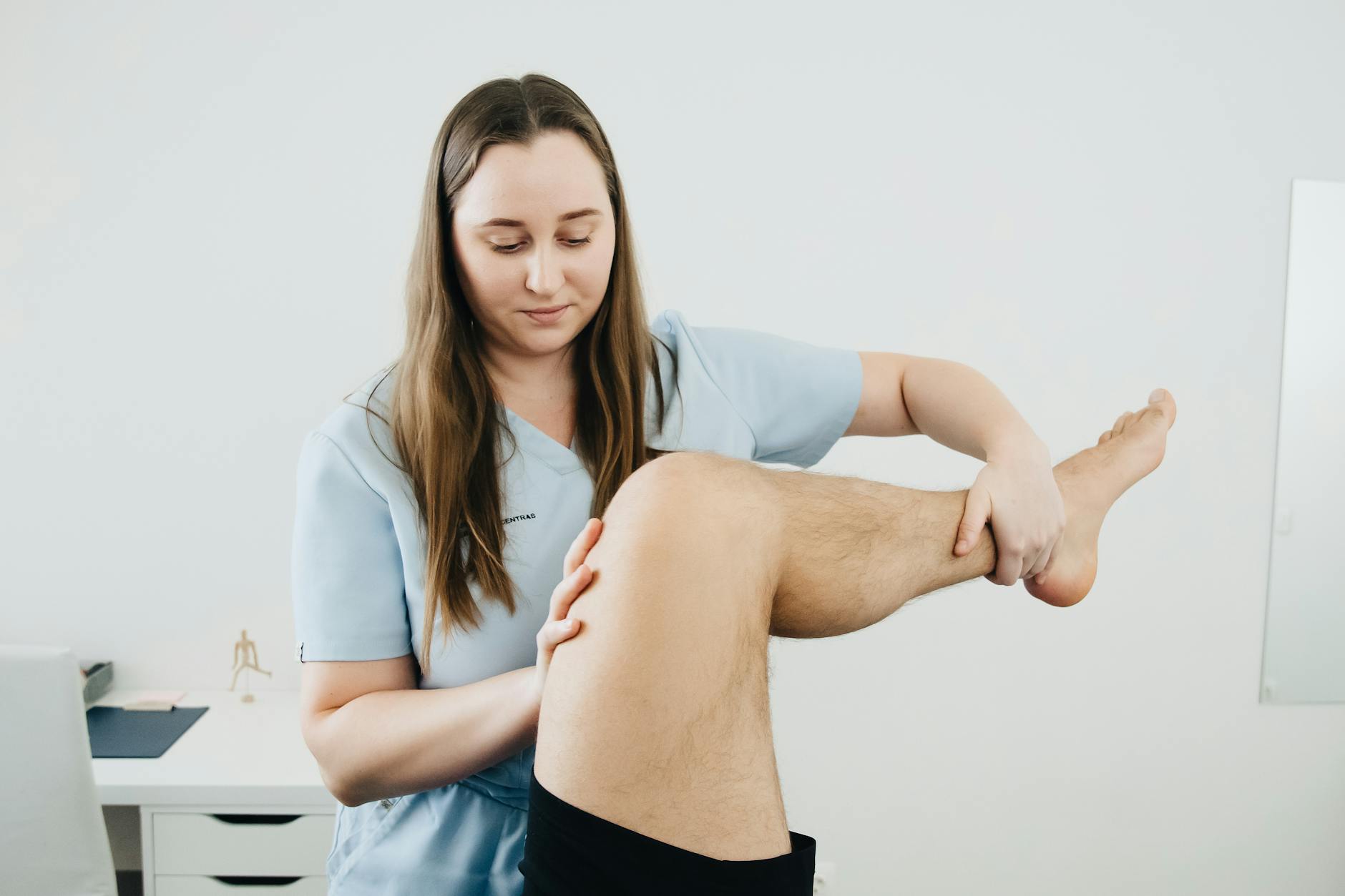 Fizjoterapeuta prowadzi ćwiczenia rehabilitacyjne z nogą pacjenta