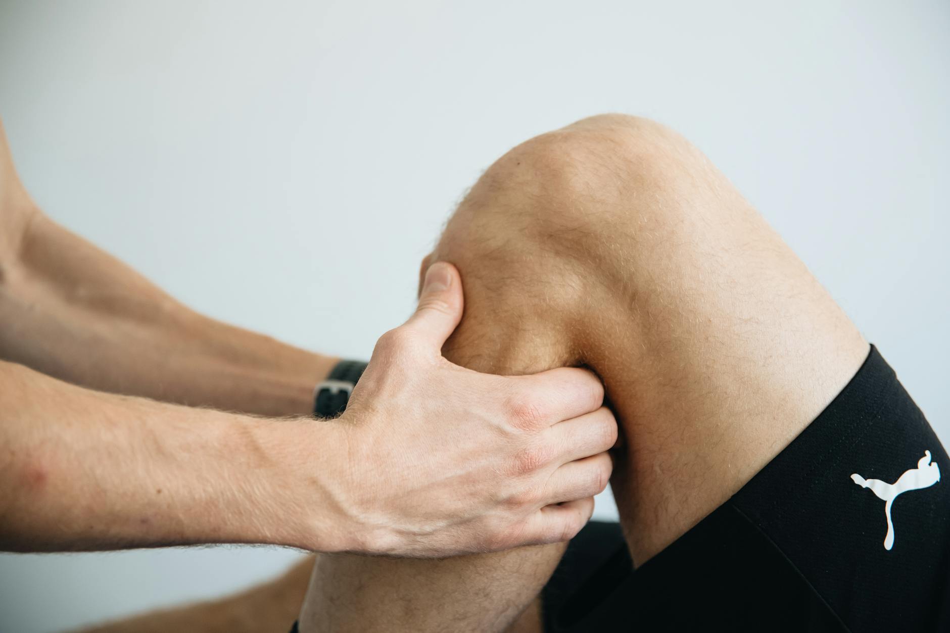 Fizjoterapeuta wykonuje masaż kolana pacjenta po operacji