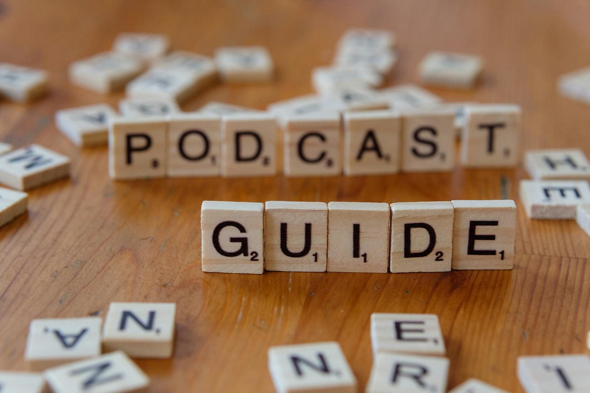 Kafelki Scrabble układające napis Podcast Guide na drewnianym blacie