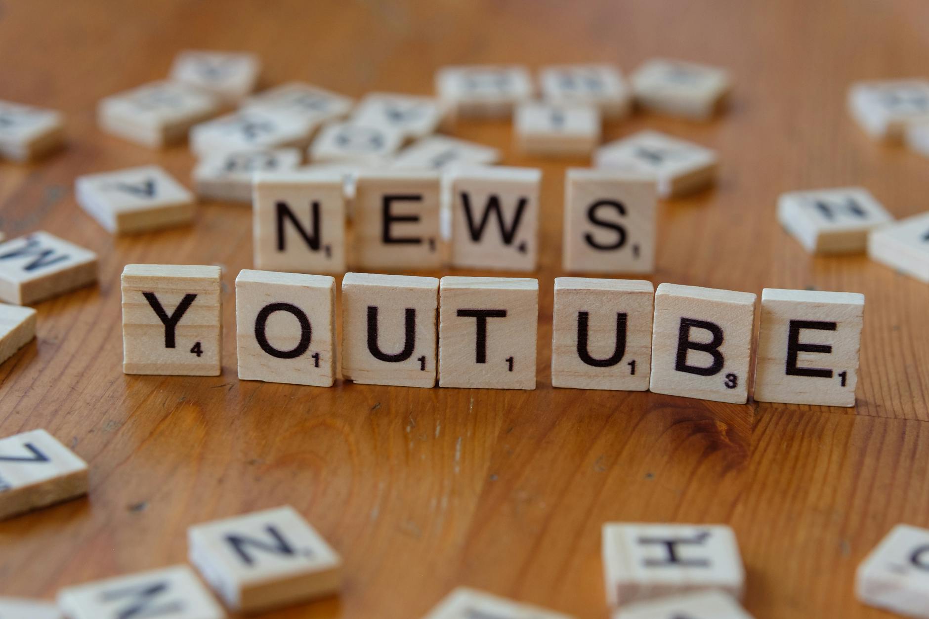 Kafelki Scrabble z ułożonymi słowami YouTube i News na drewnianym blacie