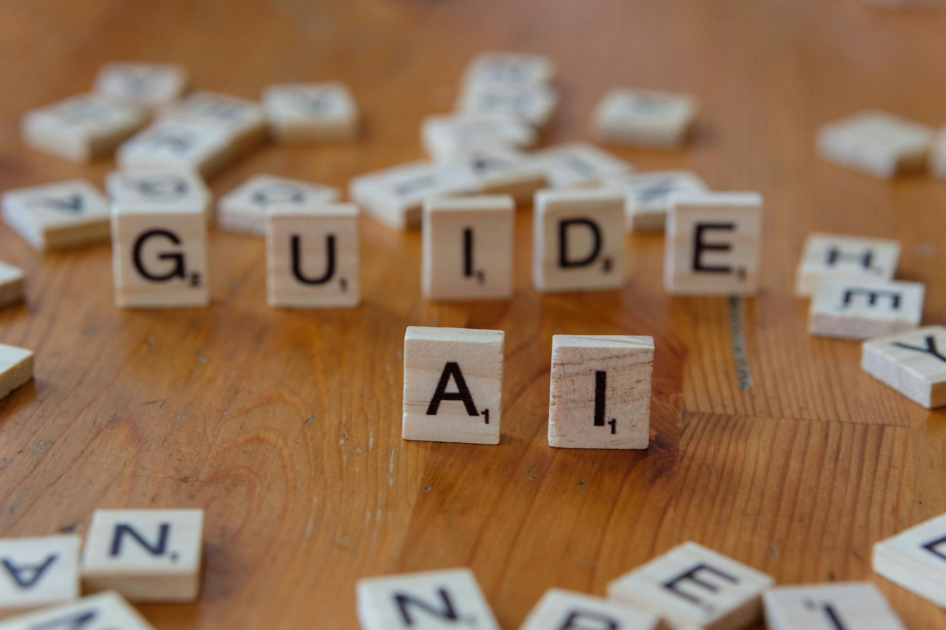 Klocki Scrabble układające słowa GUIDE i AI na drewnianym blacie