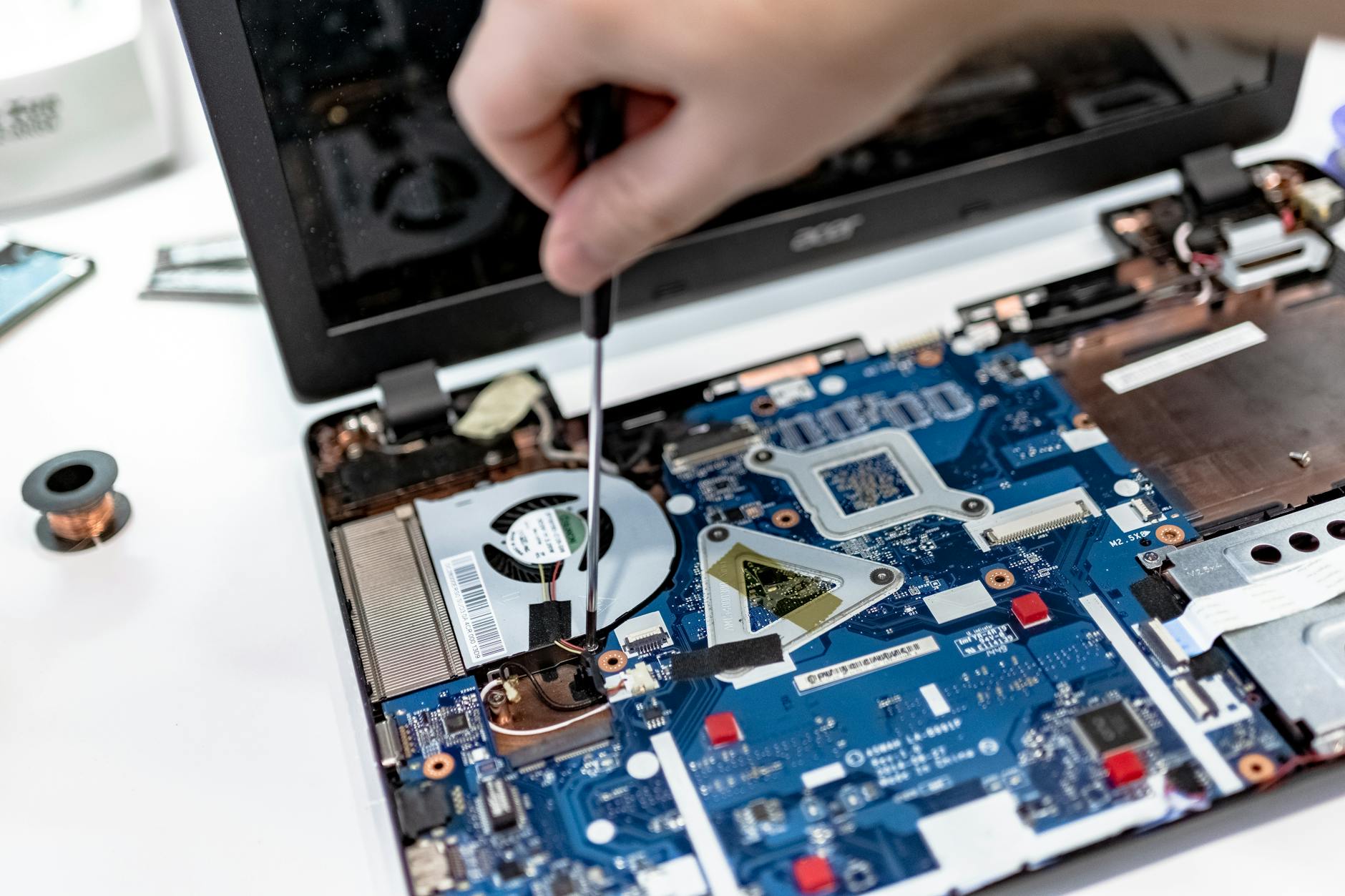 Serwisant naprawiający płytę główną laptopa śrubokrętem