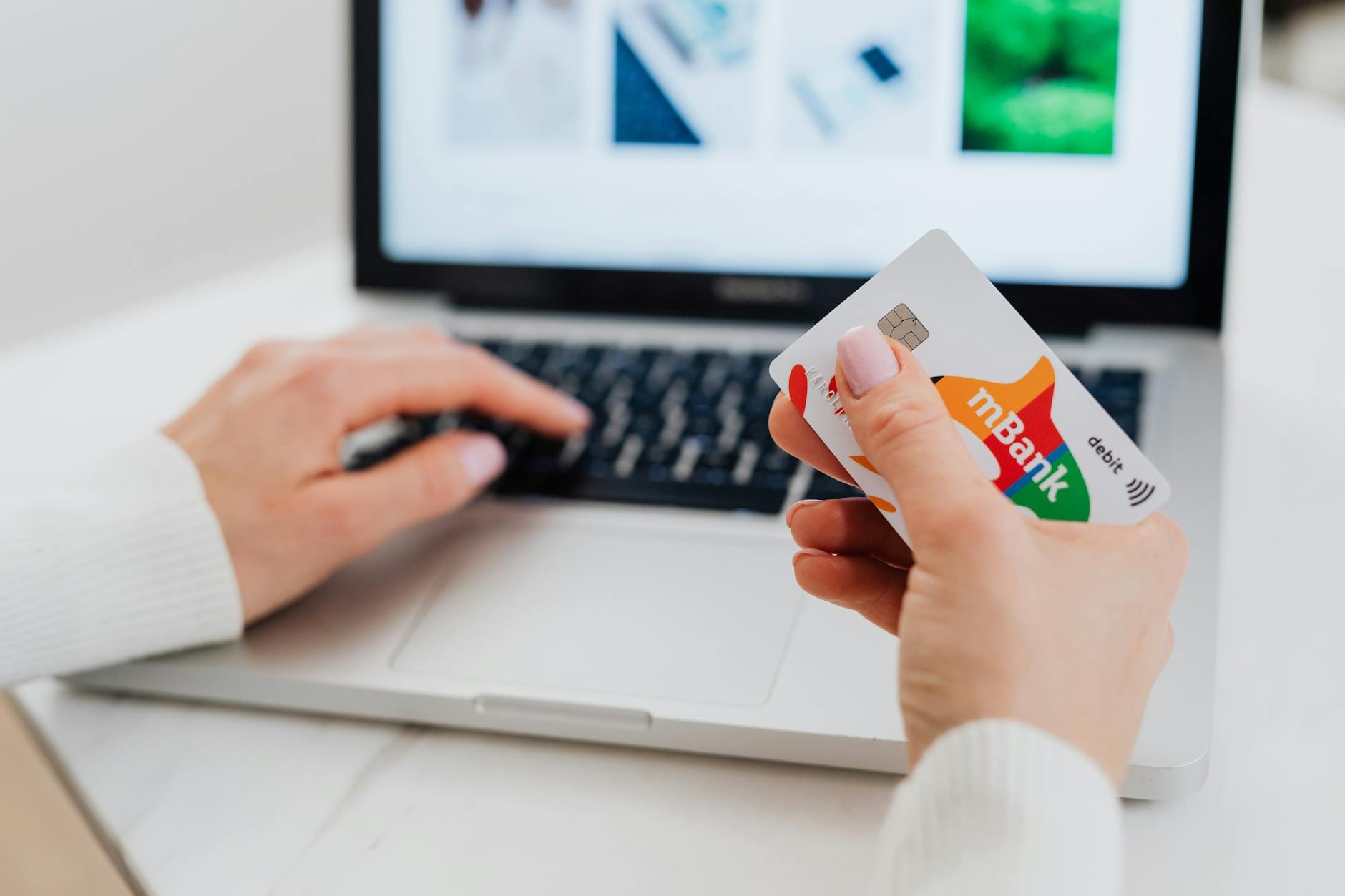 Dłonie przy laptopie z kartą kredytową podczas płatności online