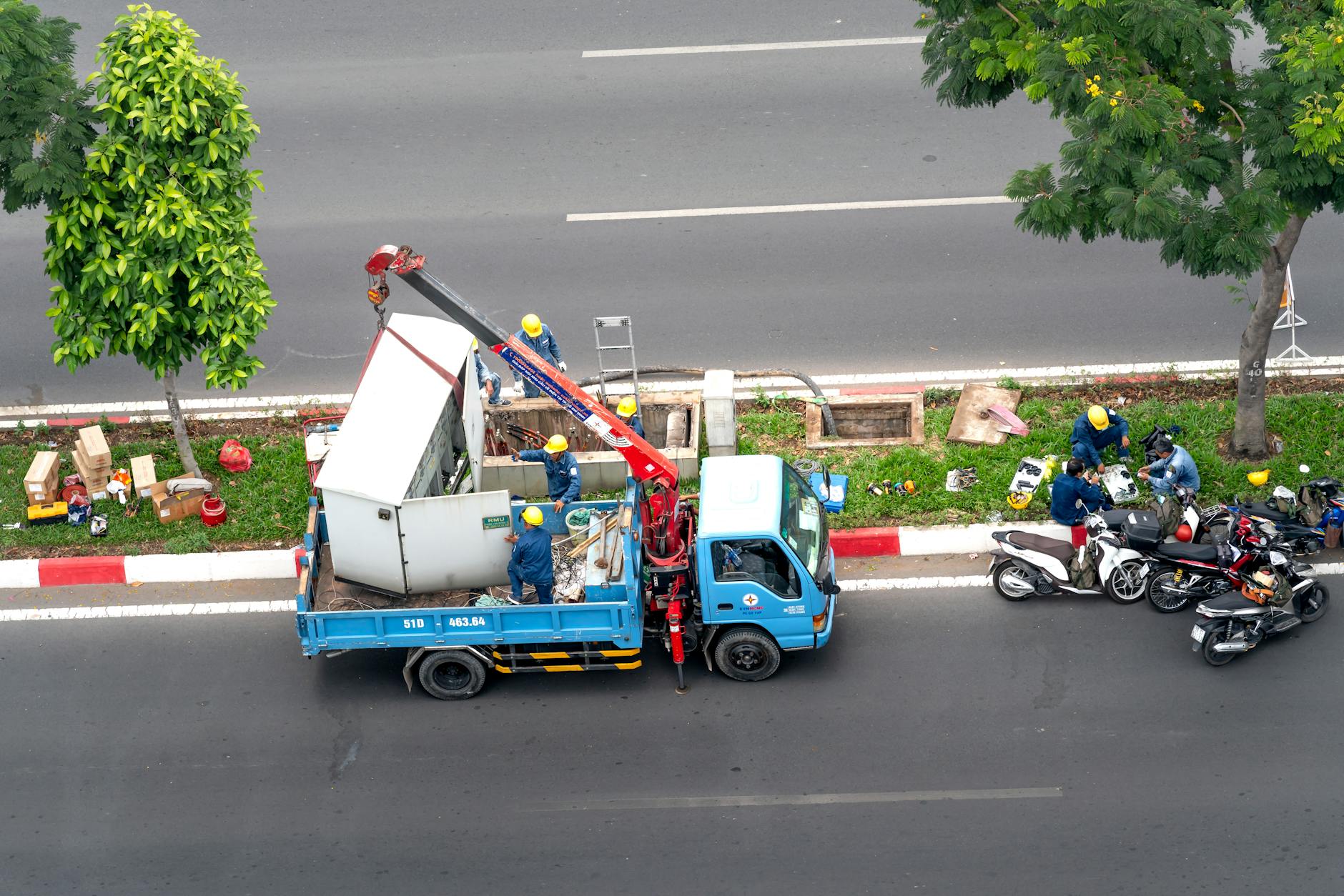 Pracownicy przy lawecie i motocyklach na miejskiej ulicy