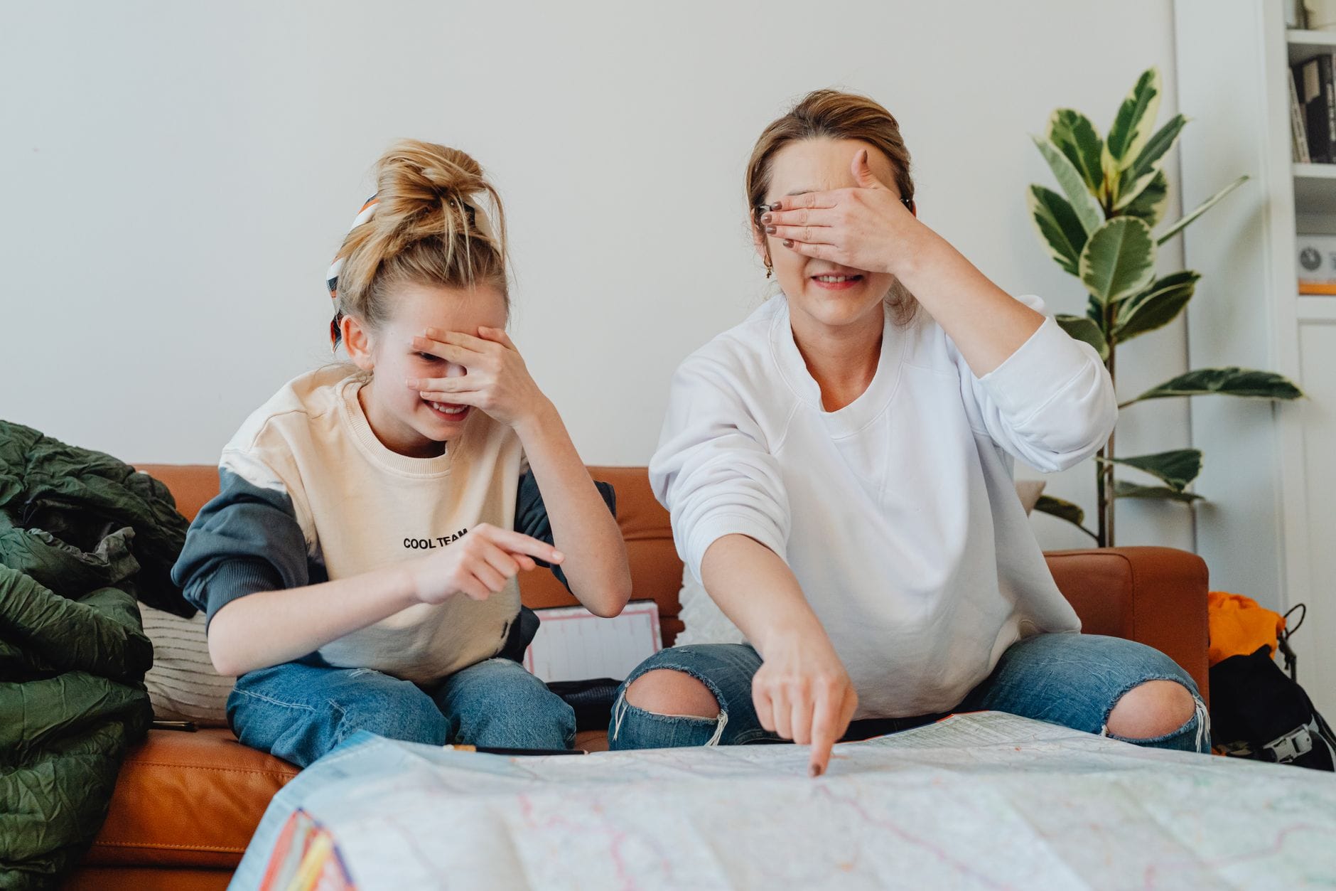 Mama z córką w domu planują rodzinny weekend, wskazując miejsca na mapie