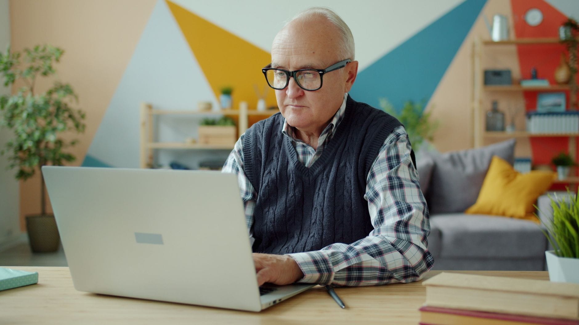 Starszy mężczyzna pracuje na laptopie w domowym biurze