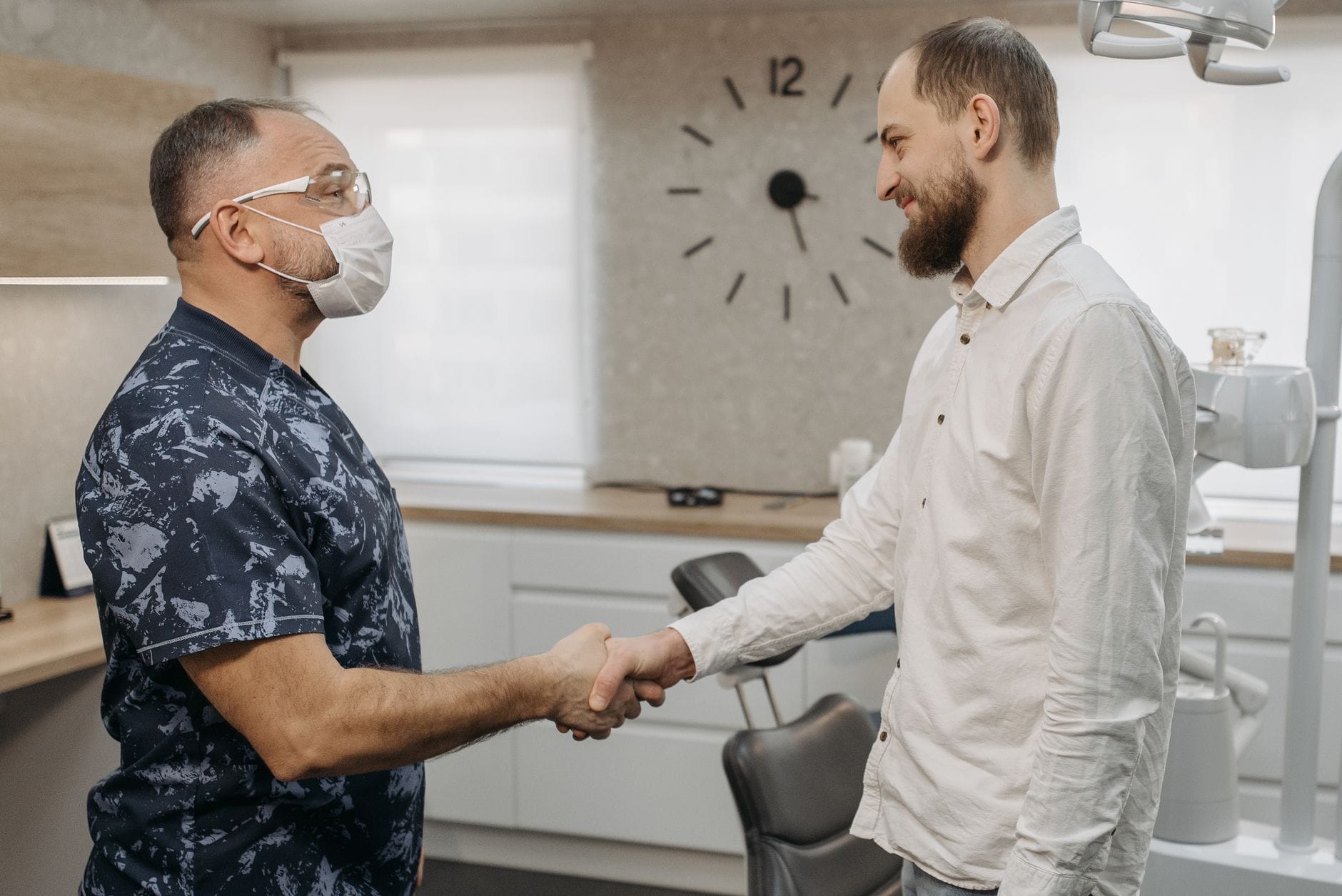 Dentysta podaje rękę pacjentowi podczas konsultacji w nowoczesnej klinice