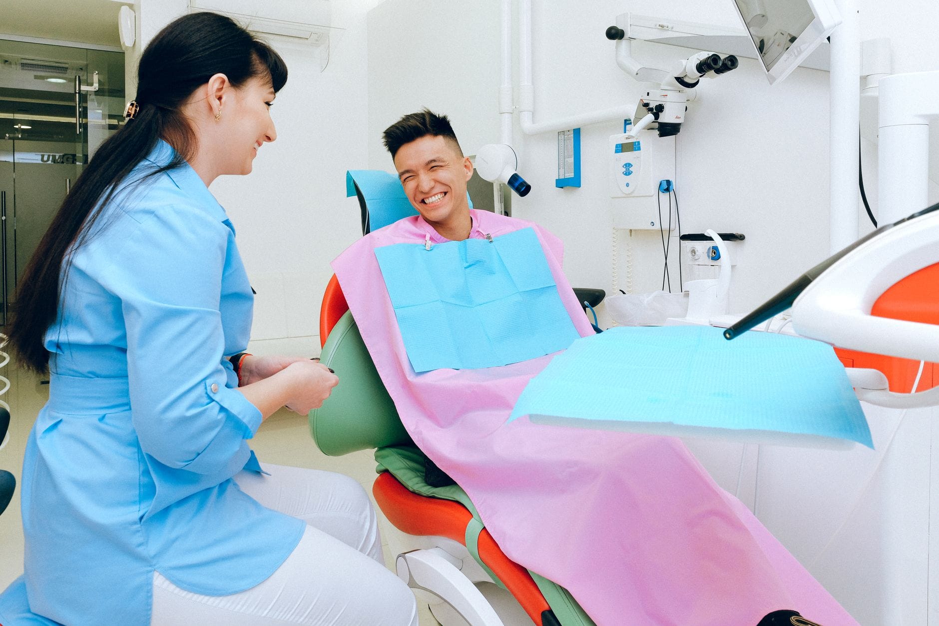 Uśmiechnięty pacjent na fotelu rozmawia z dentystką przed zabiegiem