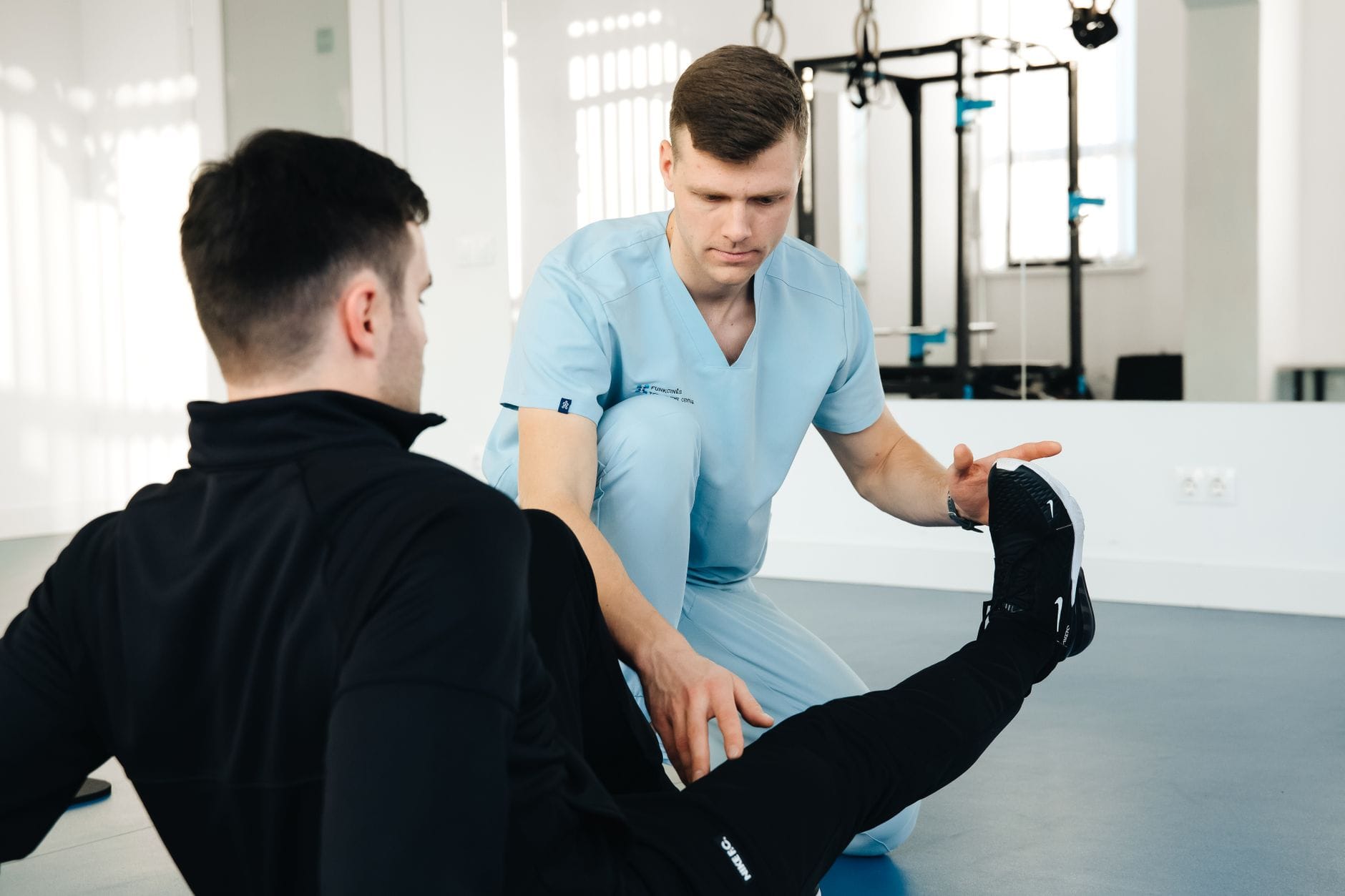 Fizjoterapeuta pomaga pacjentowi w ćwiczeniach nogi podczas rehabilitacji