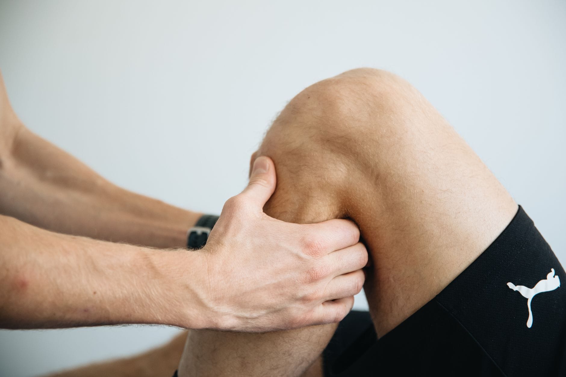 Fizjoterapeuta wykonuje masaż kolana podczas rehabilitacji sportowej